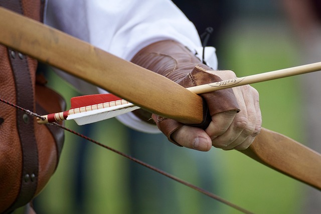 A close up photo of an archer nocking an arrow to a longbow